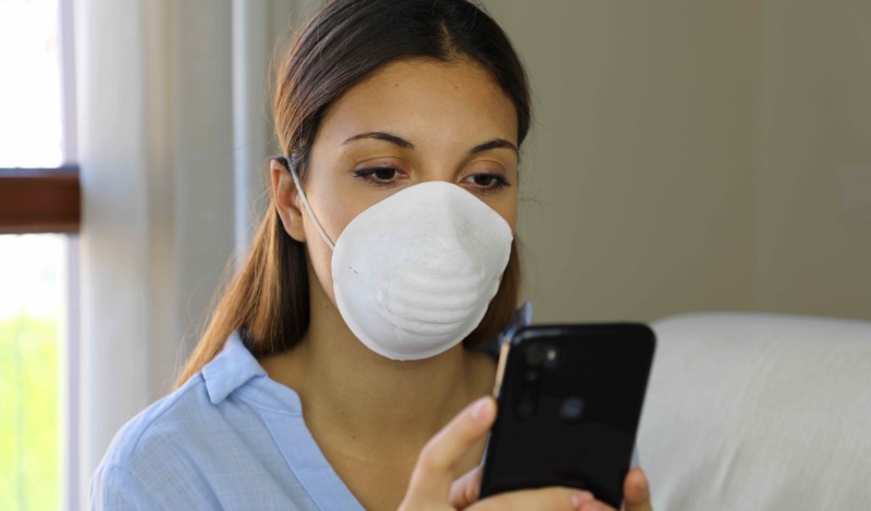 woman wearing mask looking at smartphone