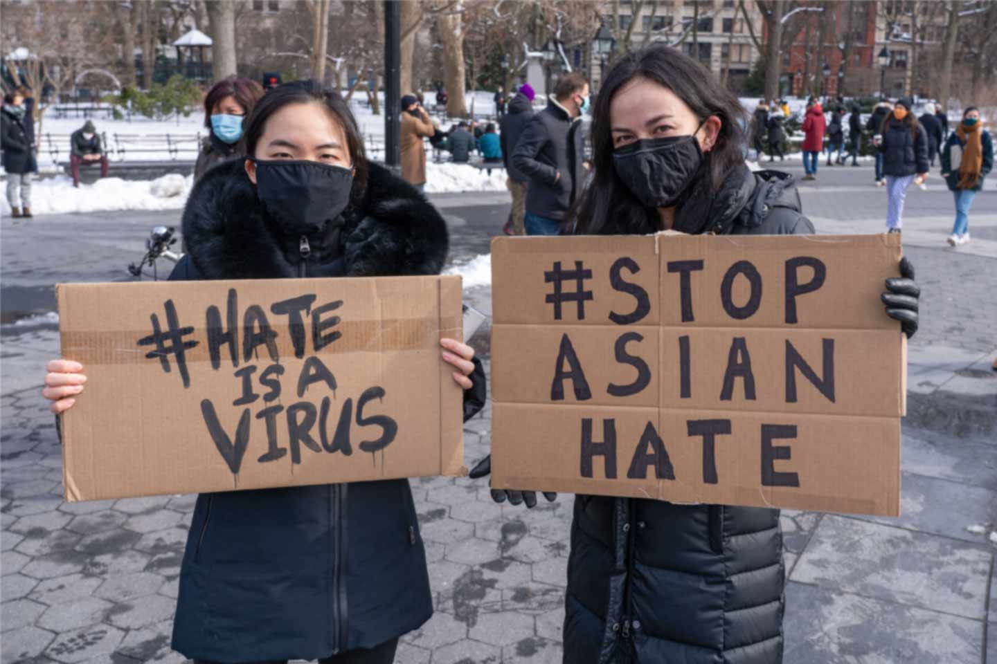 two protestors with signs bringing awareness to Asian hate