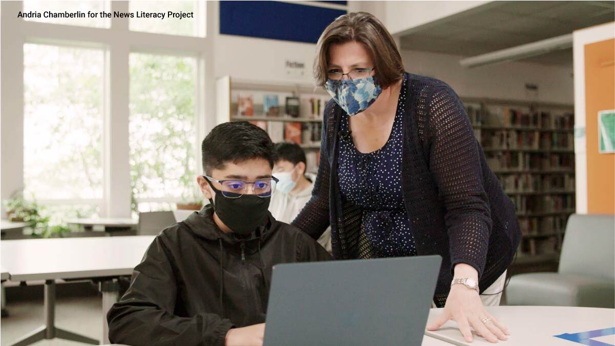 student working with a teacher in a library