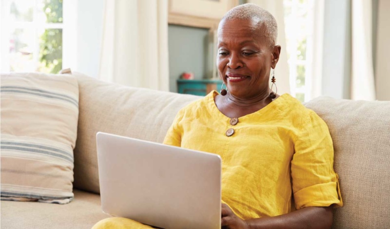 older woman sitting on a couch using her laptop