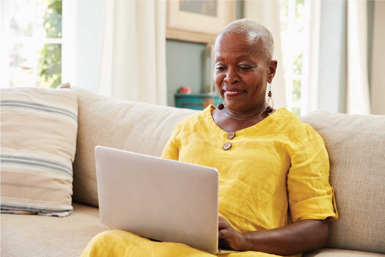 older woman sitting on a couch using her laptop