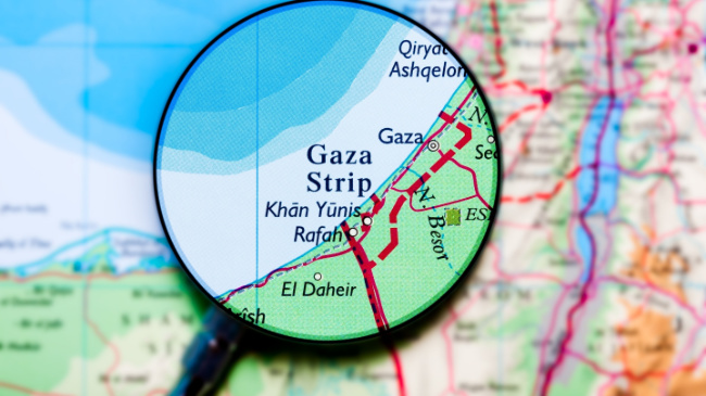 A magnifying glass hovers above Gaza on a regional map.
