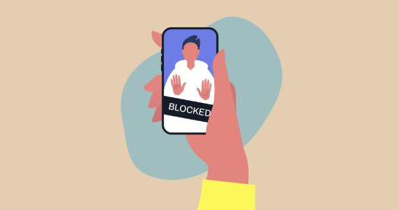 An illustration of a hand holding a smartphone. On the phone’s screen, a person has their hands up with the word “blocked” superimposed. 