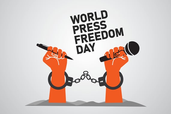 An illustration of two raised hands holding a microphone and pen while in handcuffs. The hands are beneath the words “World Press Freedom Day.”