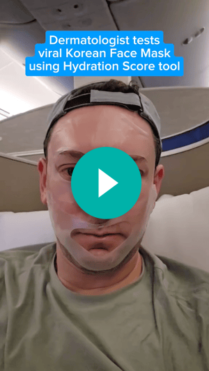 A screenshot of a video of a man sitting in an airplane and wearing a hydrating skin mask. Text says, “Dermatologist tests viral Korean Face Mask using Hydration Score tool.” A teal play button is over the man’s face.