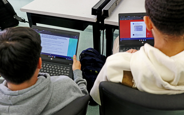 Two students work on a Checkology lesson on their laptops during class.