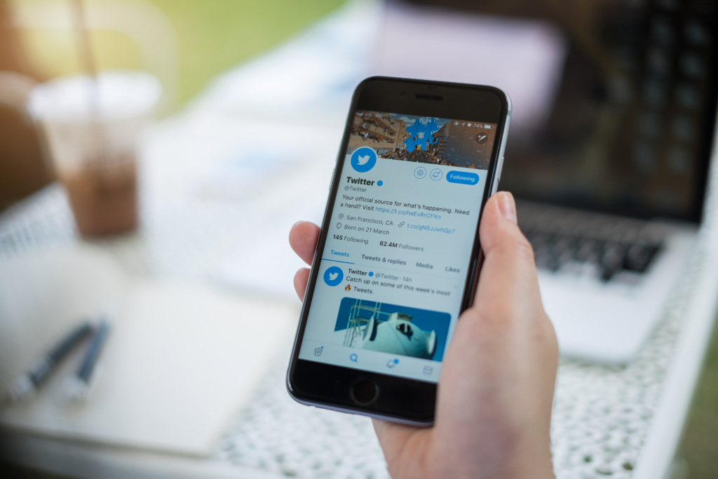 Person holds phone with Twitter open on the screen.