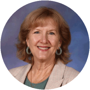 head and shoulders photo of Kalynne Pudner, a smiling woman with reddish-blond hair, hoop earrings and a beige blazer and green shirt.