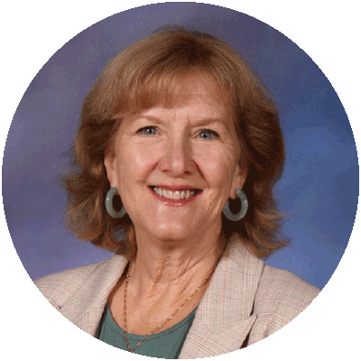 head and shoulders photo of Kalynne Pudner, a smiling woman with reddish-blond hair, hoop earrings and a beige blazer and green shirt.